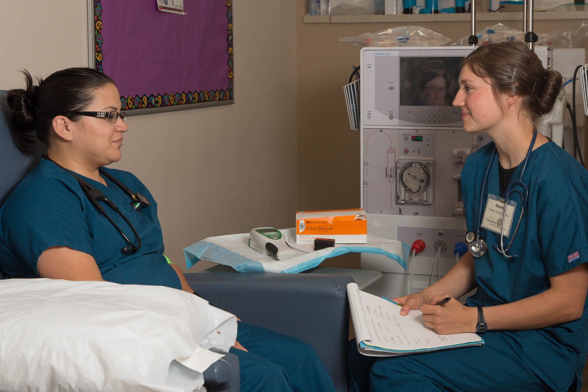 Two medical assistants sitting and talking in a medical office